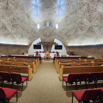 Inside the dome sanctuary — radiating wooden beams over the pews